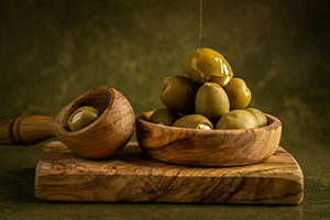wood bowl full of olives on wooden board